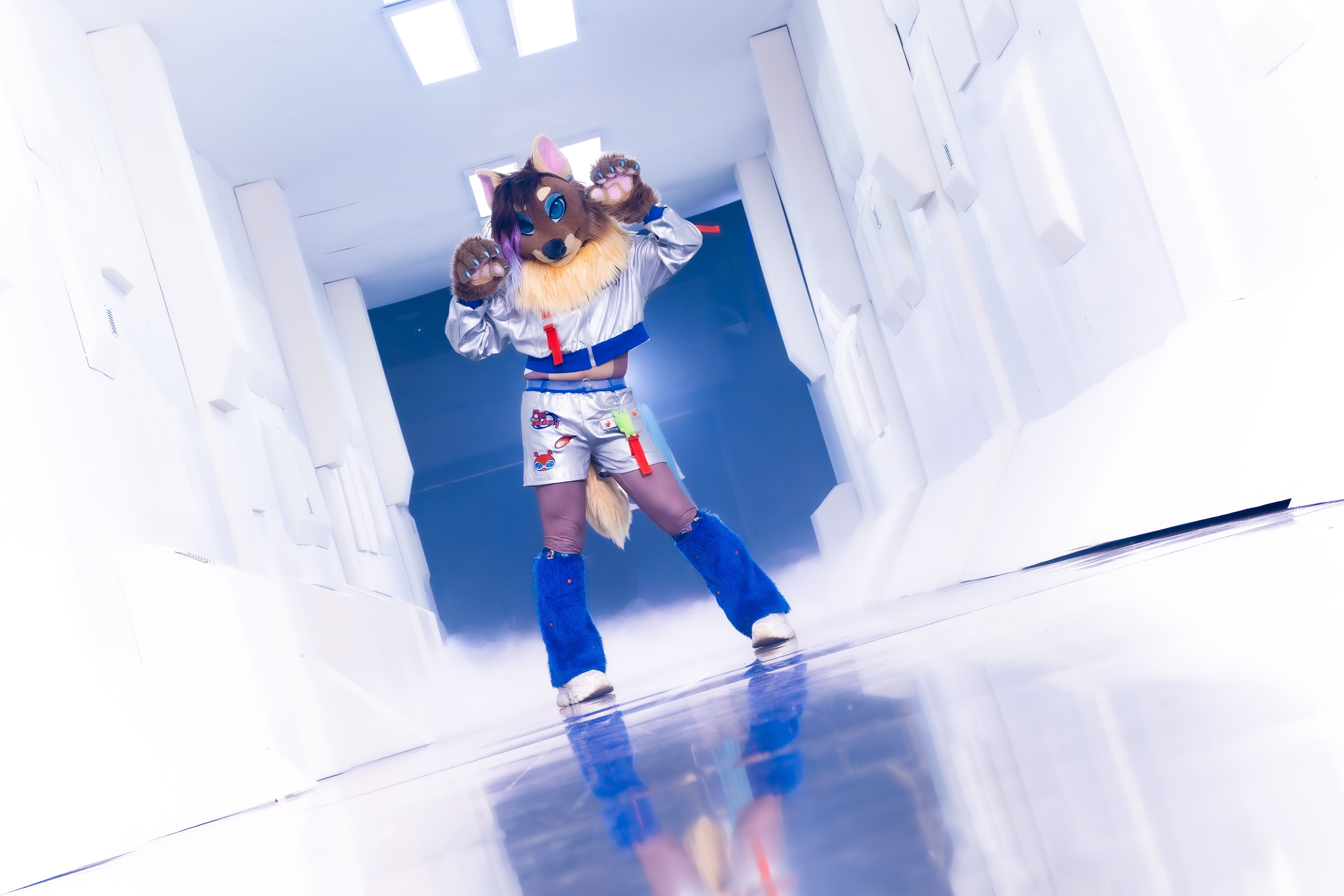 Rakukuru standing in a futuristic corridor and showing their gay little paws at the camera